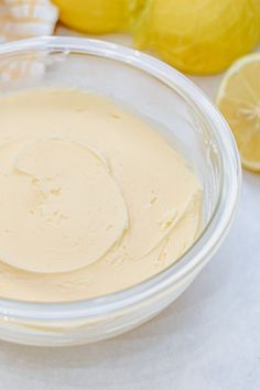 a glass bowl filled with batter next to lemons and other food on a table