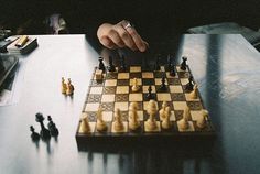 a person playing chess on a wooden table