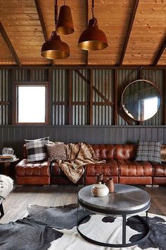 a living room with leather couches and cow hide rugs on the wooden floor