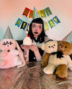 a woman sitting at a table with stuffed animals in front of her holding a piece of cake