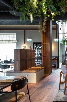 the interior of a restaurant with wooden tables, chairs and plants hanging from the ceiling