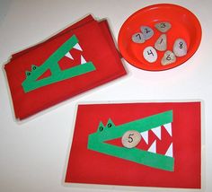 two paper plates with rocks in the shape of crocodiles on them next to a red plate