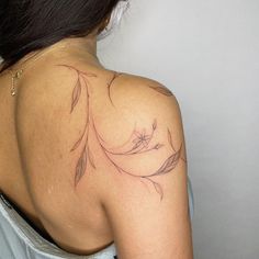 the back of a woman's shoulder with a flower tattoo on her left arm