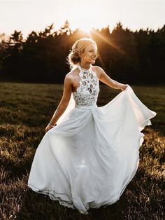 a woman in a white dress is walking through the grass with her hands on her hips