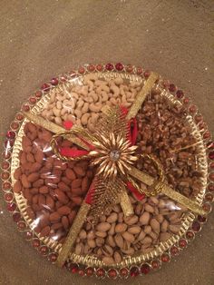 a platter filled with nuts on top of a table next to a red and gold ribbon