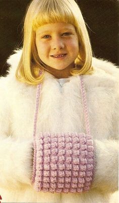 a young blonde girl wearing a pink and white crochet purse