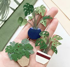 a person's hand is holding some fake plants