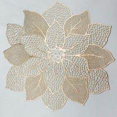 a gold doily with leaves on it is shown in the middle of a white background