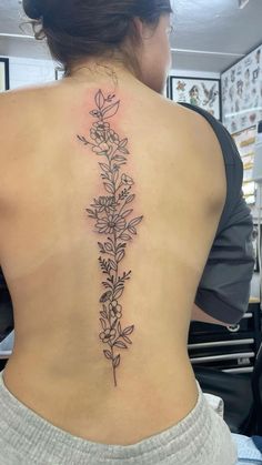 the back of a woman's lower back tattoo with flowers on her left side