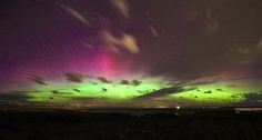 the aurora bore is glowing brightly in the night sky with clouds and stars above it