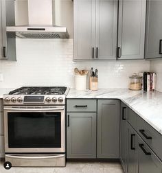 a stove top oven sitting inside of a kitchen next to gray cabinets and counter tops