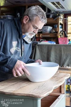 an older man is making a bowl on a wooden table in his workshop with woodworking tools