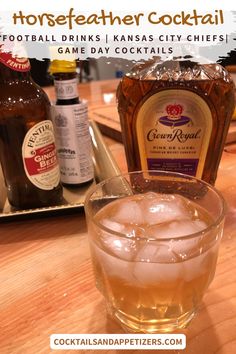 a glass filled with ice sitting on top of a wooden table next to bottles of alcohol