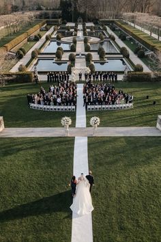 the bride and groom are walking down the aisle at their wedding ceremony in front of an elaborate garden