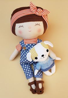 a doll holding a stuffed animal on top of a brown tablecloth background with white polka dots