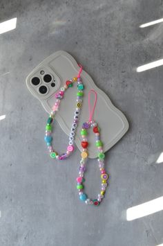 two cell phones are sitting on the ground next to some beaded bracelets and a phone case