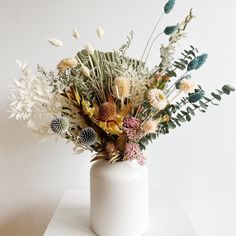 a white vase filled with lots of different types of flowers