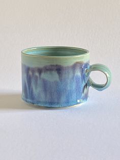 a blue and green cup sitting on top of a white table