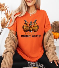 Chicken Witches Funny Halloween T-Shirt, Halloween Chicken Tonight We Fly Shirt, Vintage Chicken Witch Shirt, Funny Chicken Halloween Shirt **Product Overview   We proudly offer shirts from the Bella Canvas and Gildan SoftStyle collections, both recognized for their superior industry standards. *Bella Canvas:*   - Available in unisex sizing   - Lightweight fabric at 4.2 oz   - Solid colors are crafted from 100% Combed and Ring-Spun Cotton   - Athletic Heather contains 90% Combed and Ring-Spun Co Spooky Orange Crew Neck Top, Orange Crew Neck Top For Halloween, Funny Orange Tops For Fall, Funny Orange Top For Fall, Halloween Orange Crew Neck T-shirt, Orange Crew Neck Shirt For Halloween, Funny Orange Crew Neck Top, Novelty Short Sleeve Tops For Fall, Tonight We Fly