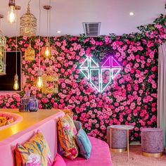 a room with pink couches and flowers on the wall, lights hanging from the ceiling