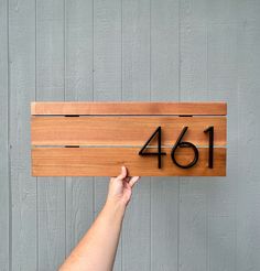 a person is holding up a wooden sign with the number forty six on it,