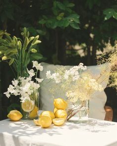 flowers and lemons sit on a table outside