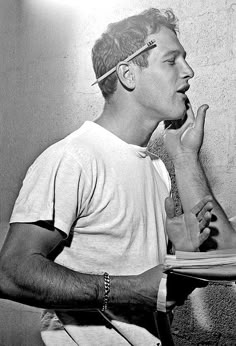 black and white photograph of a man with his hand on his mouth while reading a book