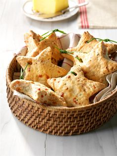 a basket filled with crackers on top of a white table next to a plate of food