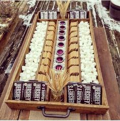 a wooden box filled with marshmallows and other items sitting on top of snow covered ground