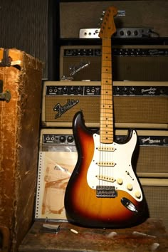 an electric guitar sitting on top of a table next to some amps and boxes