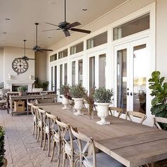 a large wooden table sitting on top of a patio next to potted planters