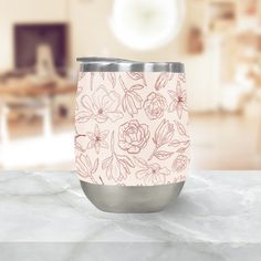 a pink and white floral pattern on a stainless steel tumbler cup sitting on a marble countertop