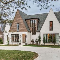 a large white house with lots of windows on it's sides and a driveway leading to the front door