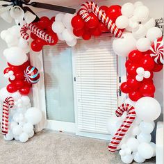 a balloon arch decorated with candy canes, balloons and streamers in front of a door