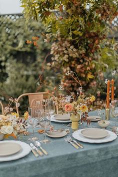 the table is set with plates, silverware and flowers in vases on it