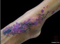 a person's foot with flowers on it and a tree branch in the middle