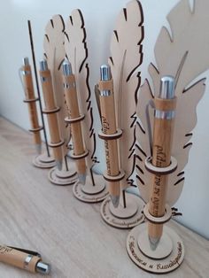 four wooden pens are lined up next to each other on a table with an oak pen holder