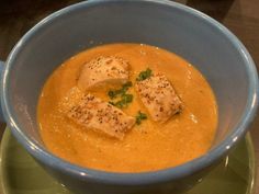 a blue bowl filled with soup on top of a green plate