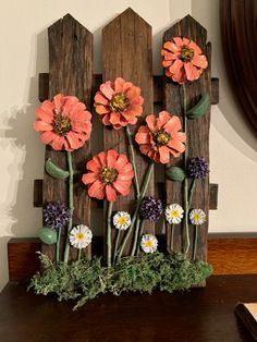 an arrangement of flowers is placed on a wooden fence in front of a wall with a mirror