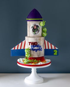 a two - tiered birthday cake with monsters on the top is decorated like a rocket ship