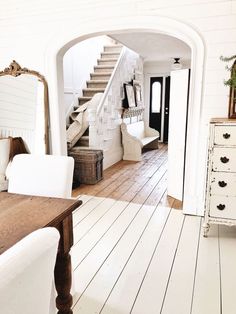 an archway leads to the living room and dining area in this white country style home