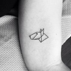 a black and white photo of a small tattoo on the left inner arm with an origami horse