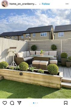 an outdoor seating area with wooden benches and potted plants on the grass in front of a fence