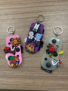 three key chains with cartoon characters on them sitting on top of a wooden table next to each other