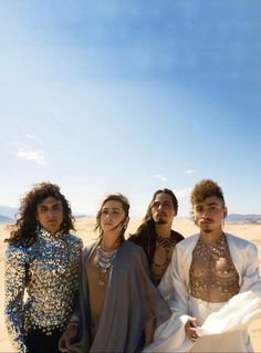 four people standing in the desert posing for a photo