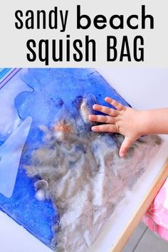 a child's hand is on top of a blue and white beach squish bag