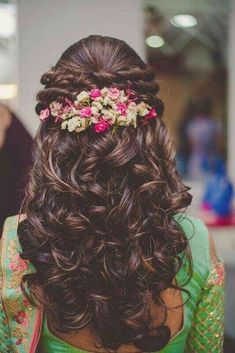 the back of a woman's head with long hair and flowers in her hair