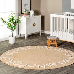 a baby's room with a rug that says welcome home on it and a crib in the background