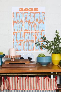 a wooden table topped with plates and bowls filled with food next to a poster on the wall