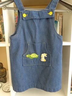 Toddler 1970's Blue Denim Sum Dress/Jumper by Tiny Folks 50 % Polyester 50% Cotton 6 1/4 X 5 Inch Front Pocket with Rabbit & Turtle Appliques 4 Yellow Strap Buttons MEASUREMENTS (in inches): Shoulder to Shoulder (back): 8 Chest: 24 Waist: 26 Hips: 28 Side Length (armpit to hem): 12 Arm Length (armpit to cuff): Sleeveless Neck Opening: 20 Square / 1 Inch Straps Bib Top to Hem: 17 / 1 Inch Hem INTERNATIONAL CUSTOMER?? Please email for Shipping Info Vintage Denim Blue Denim Dress With Pockets, Blue Denim Sleeveless Shortalls, Sleeveless Denim Blue Shortalls, Vintage Blue Denim Dress With Pockets, Vintage Blue Sleeveless Denim Dress, Retro Cotton Denim Dress With Pockets, Retro Sleeveless Cotton Denim Dress, Retro Sleeveless Denim Dress, Vintage Cotton Shortalls For Spring